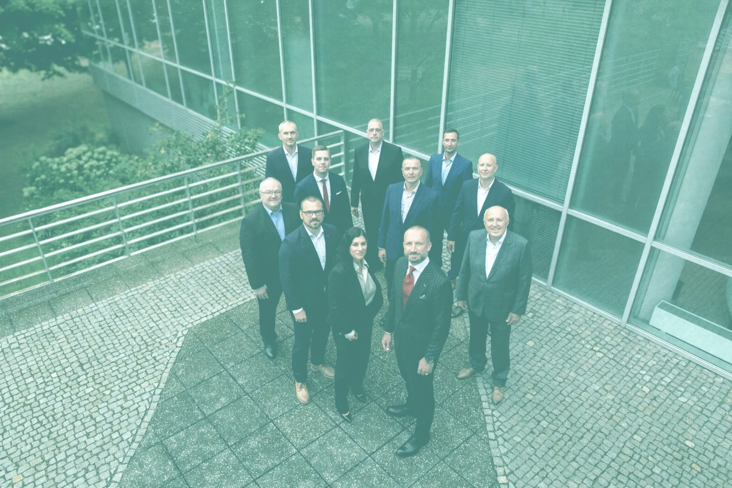 Group of people in suits in front of glass window